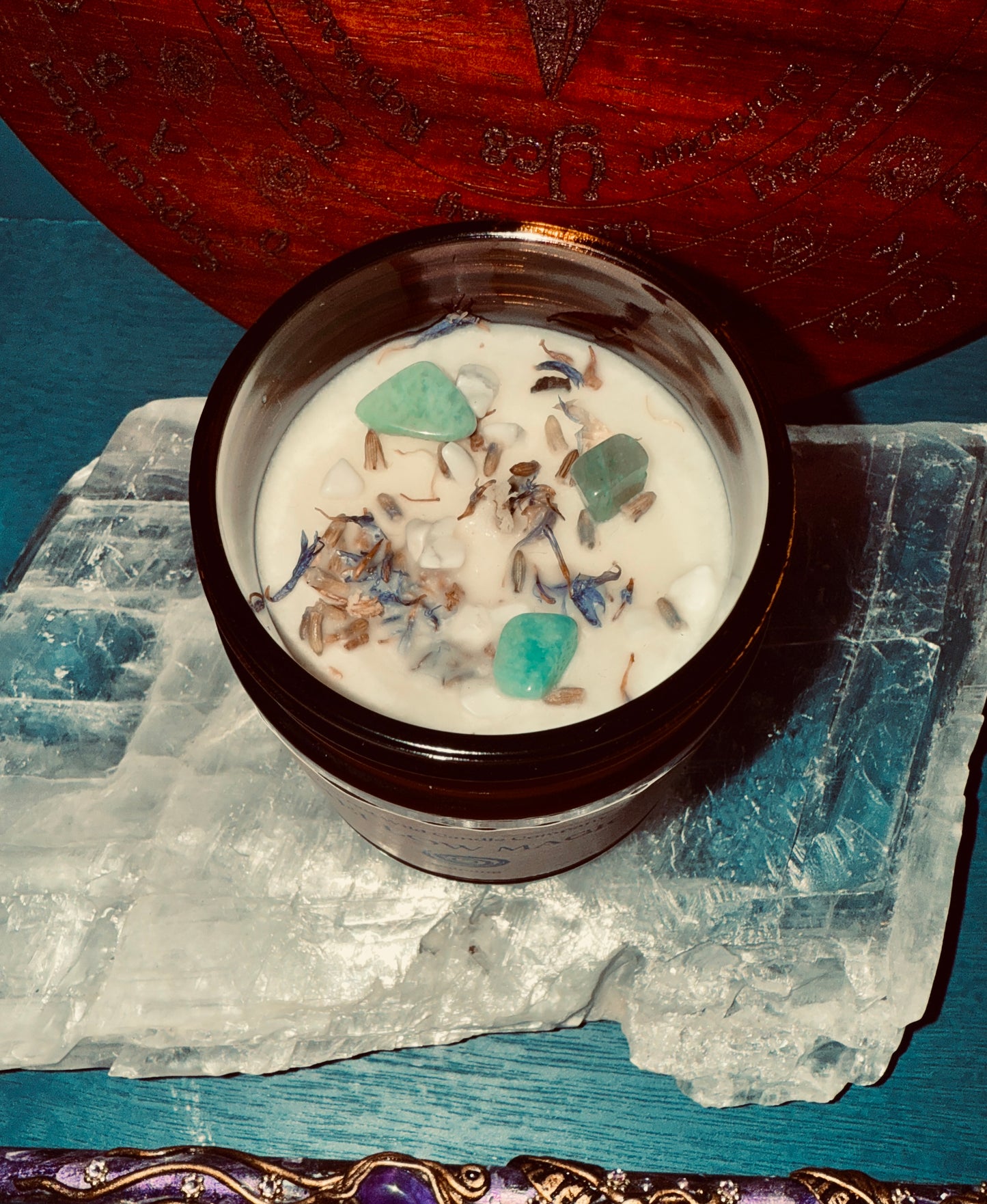 Candle in a wooden container with decorative elements on a blue stone surface