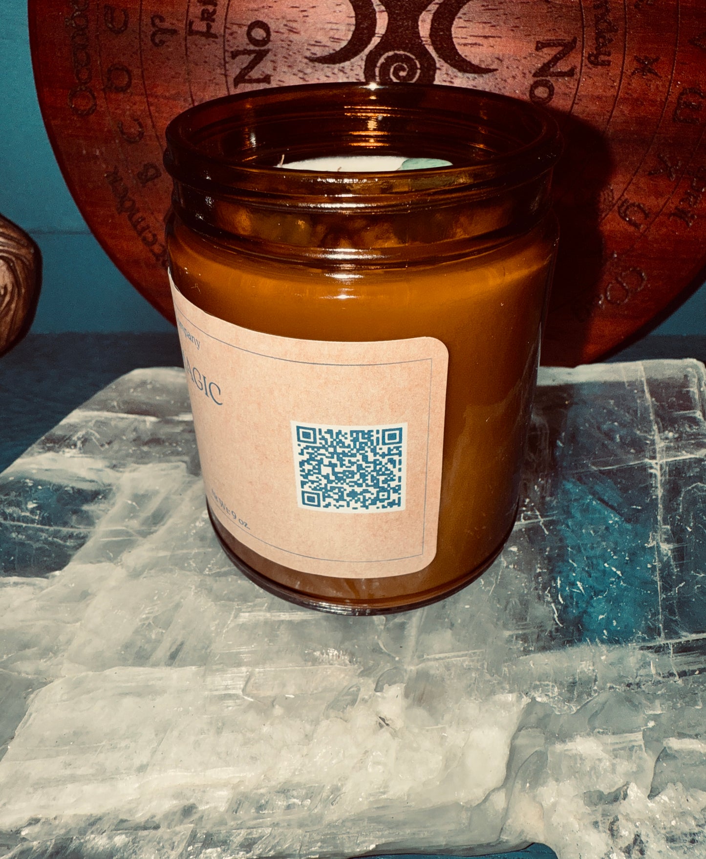 Brown candle jar with a label and QR code on a textured surface