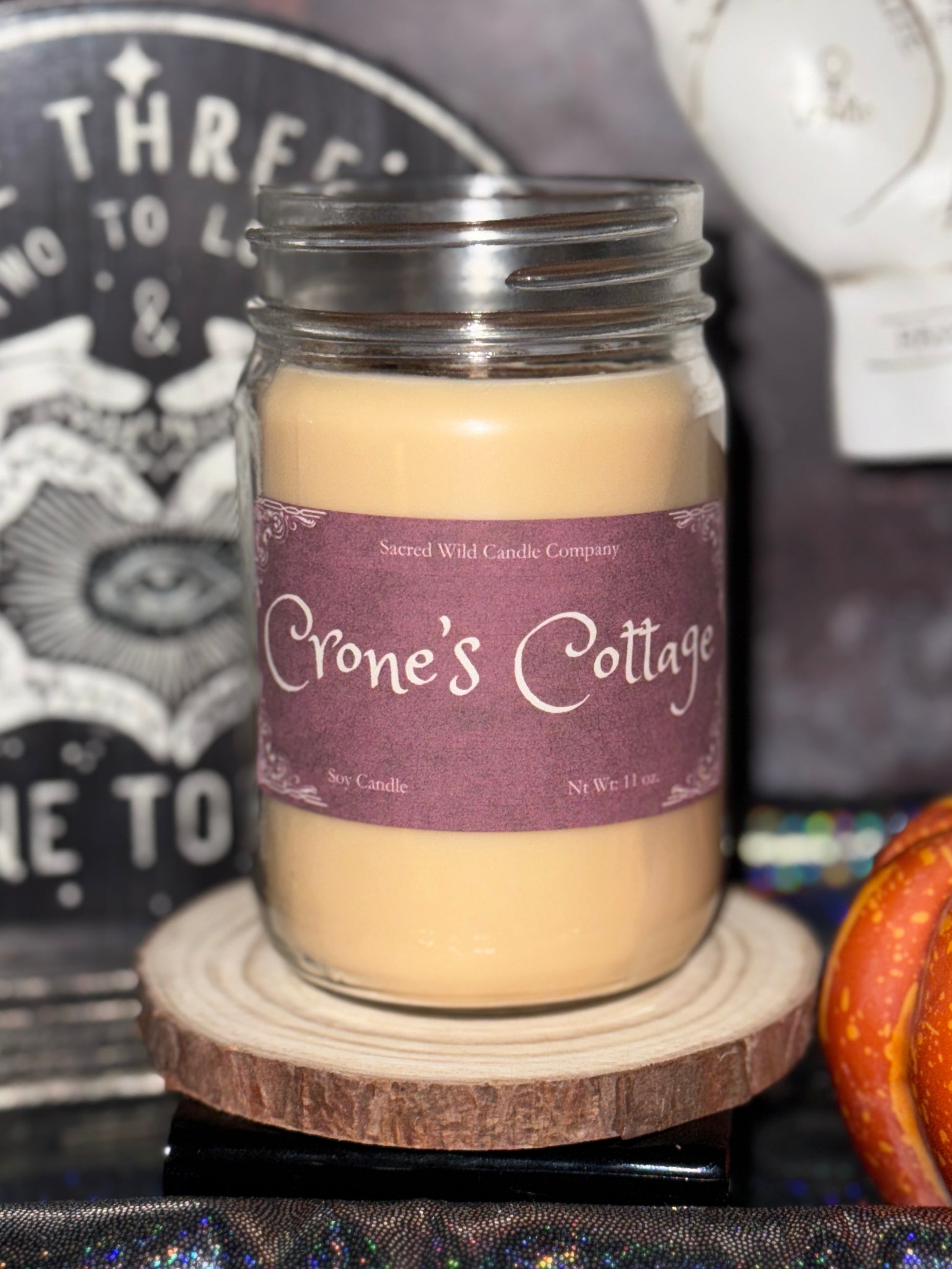 Jar candle labeled 'Crone's Cottage' on a wooden coaster with a blurred background