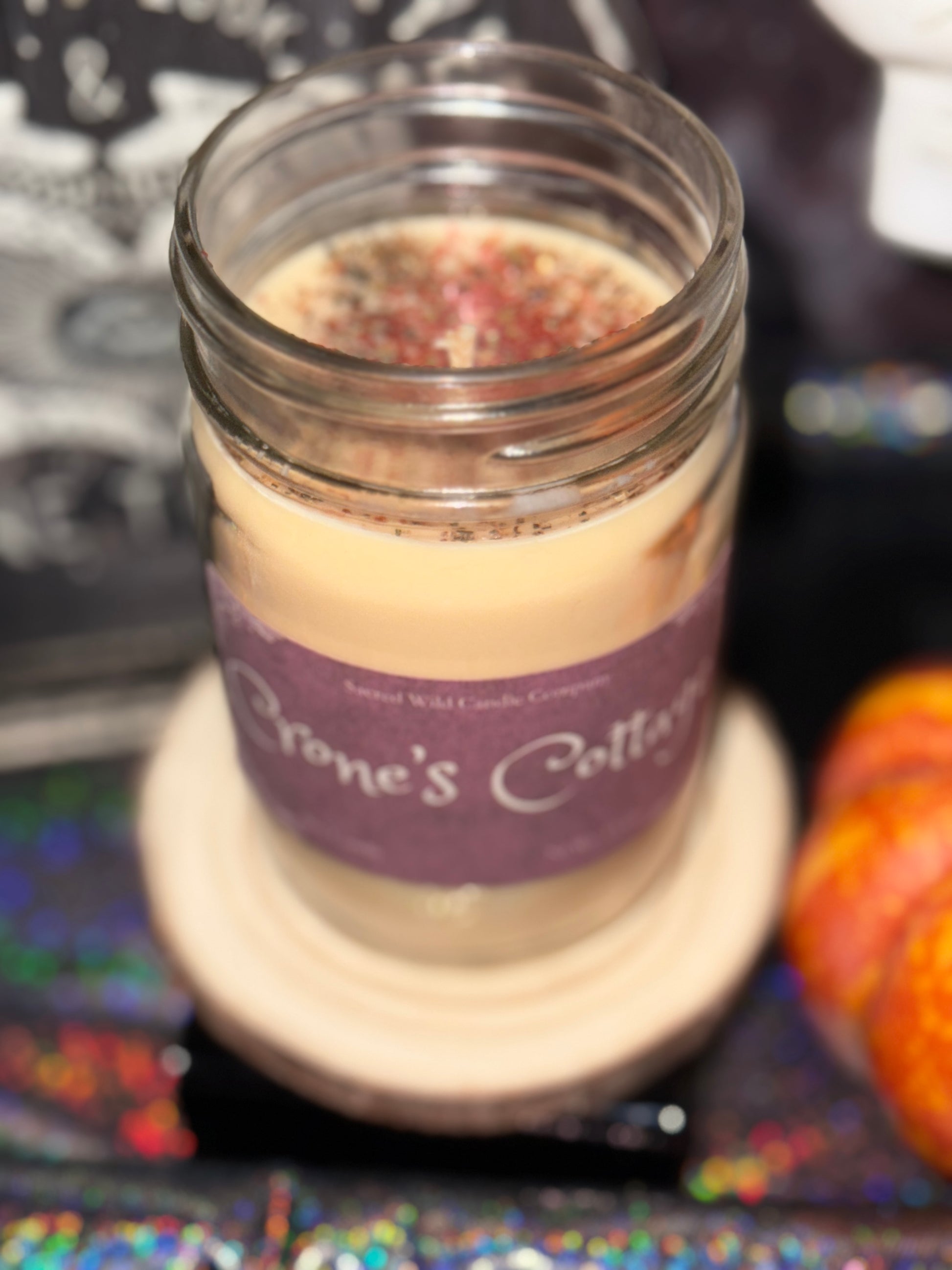 Jar candle with a purple label on a colorful surface